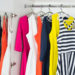 a series of bright modern fashion women's dresses on hangers in a white cupboard for summer and spring
